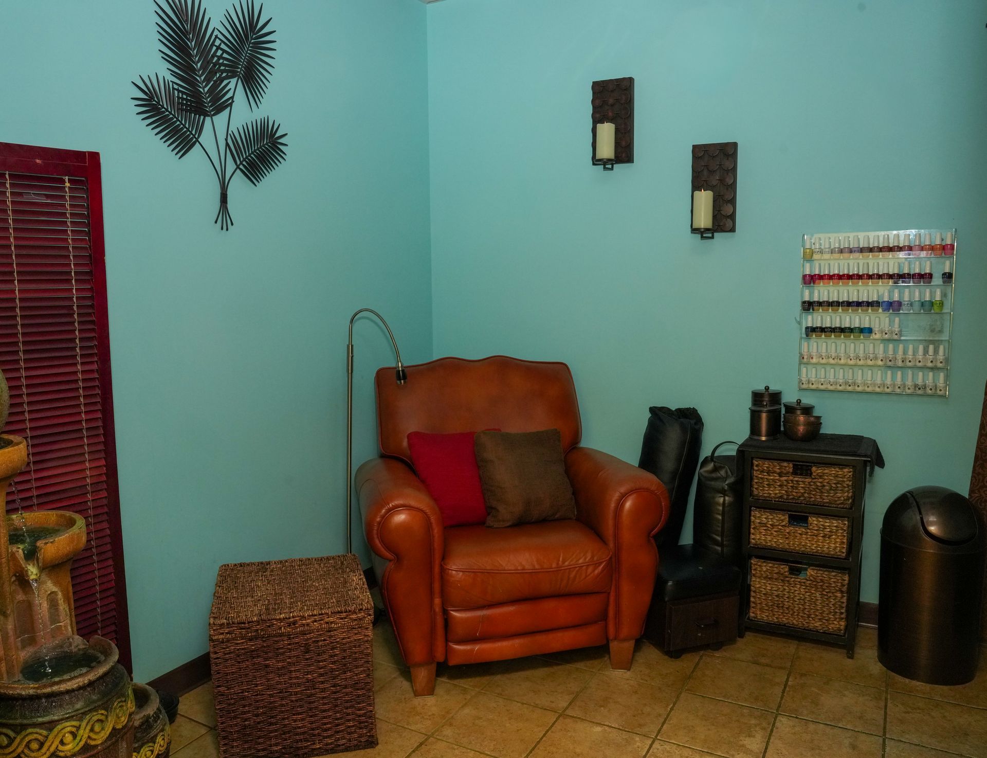Cozy room with an orange armchair, woven side table, wall decor, and teal walls on tiled floor