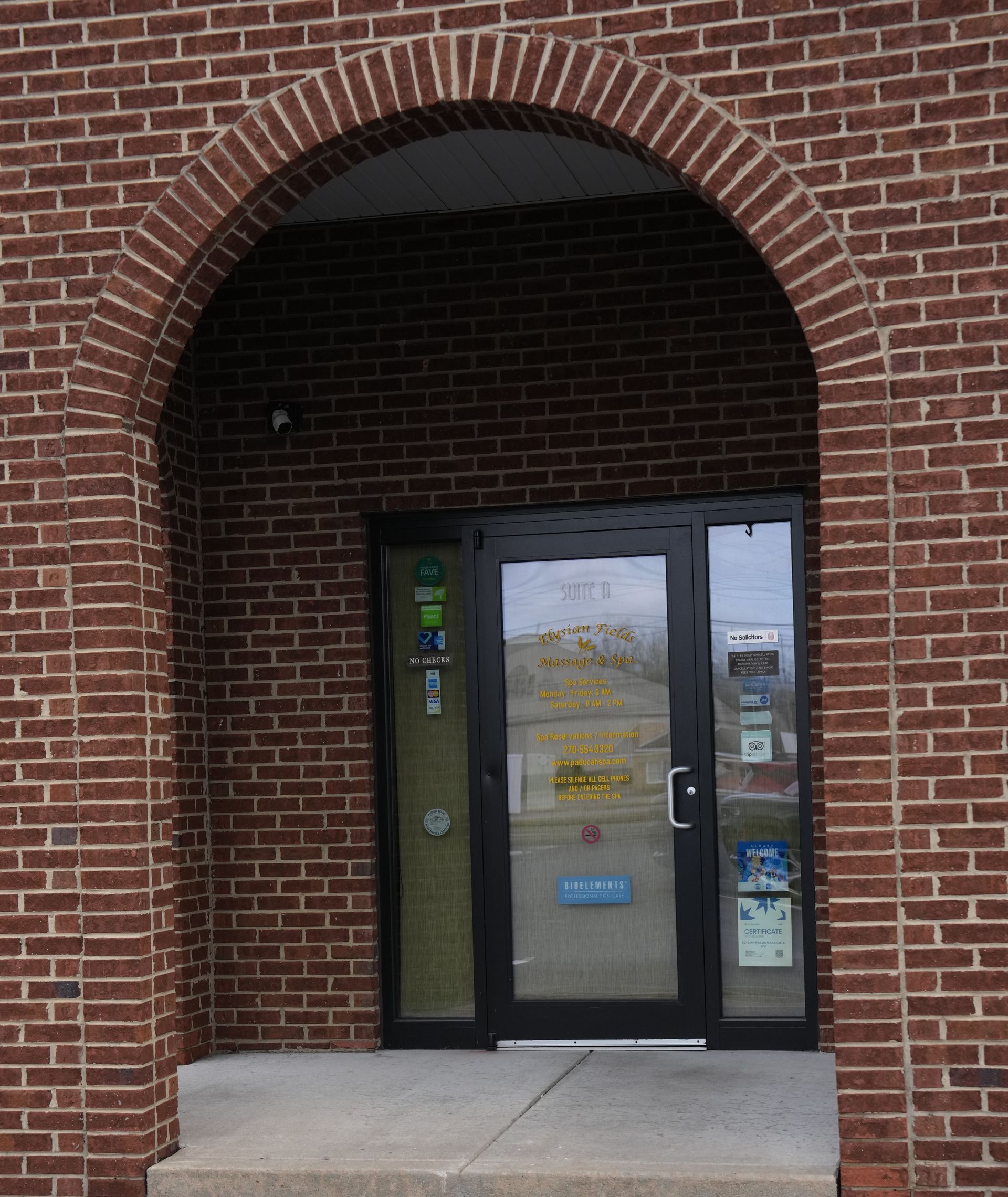 Brick building entrance with arched doorway and glass double doors under a covered entryway