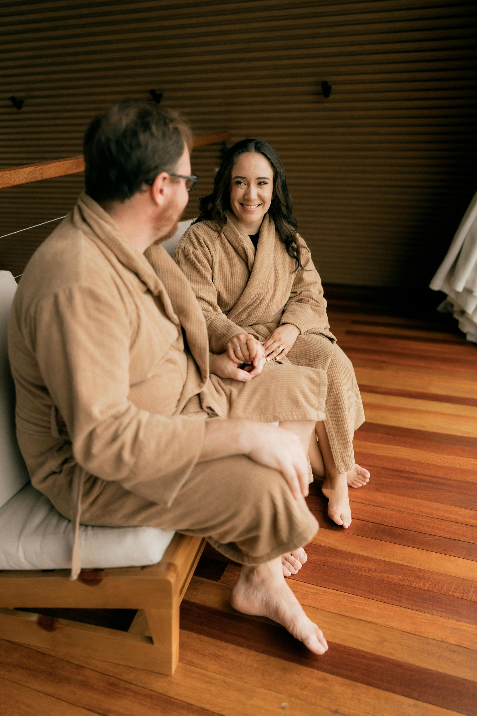 Spa therapist applying a green body wrap to a client lying face down on a massage table