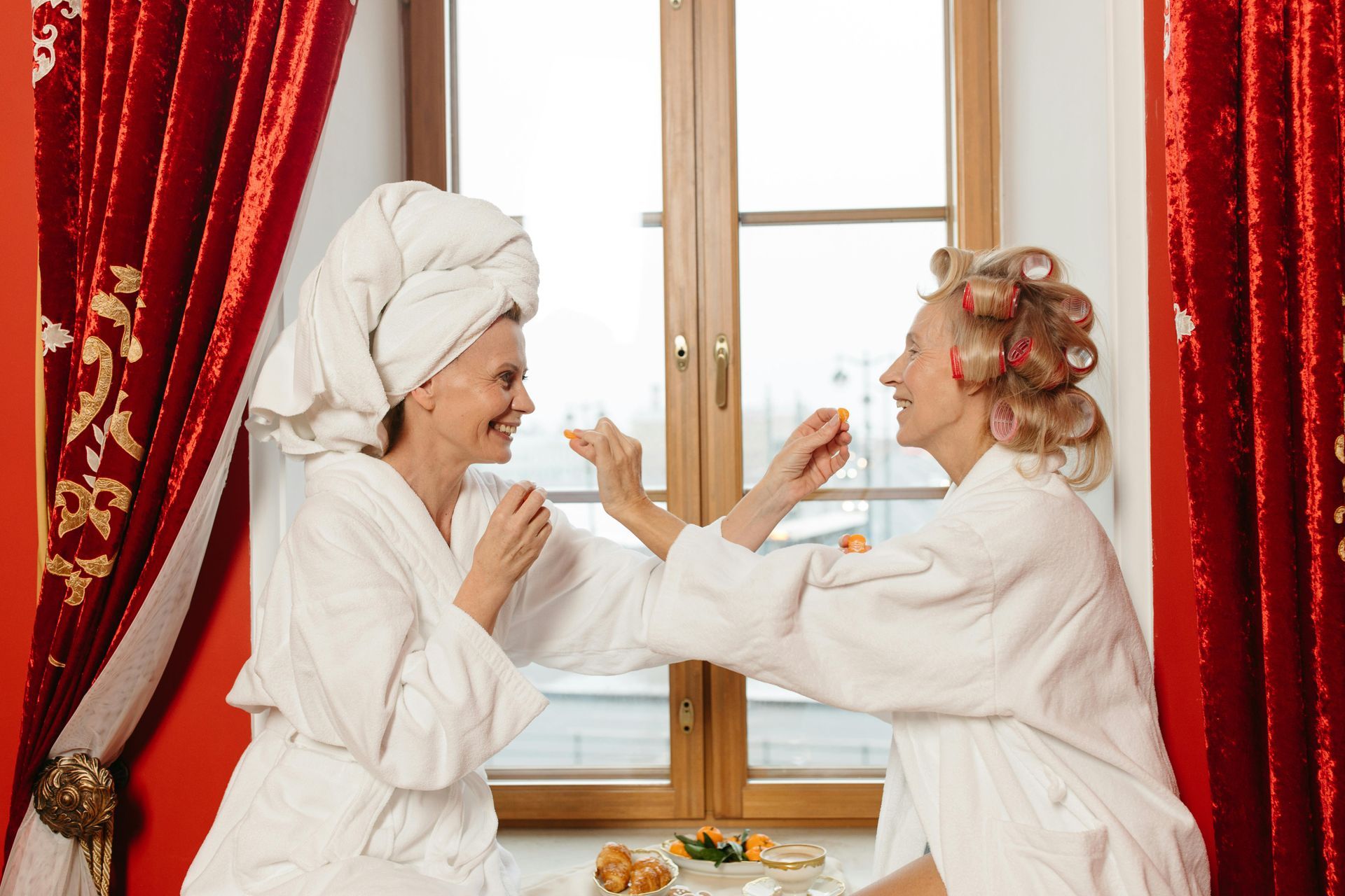 Manicurist in black gloves painting a fingernail with dark polish at a salon table