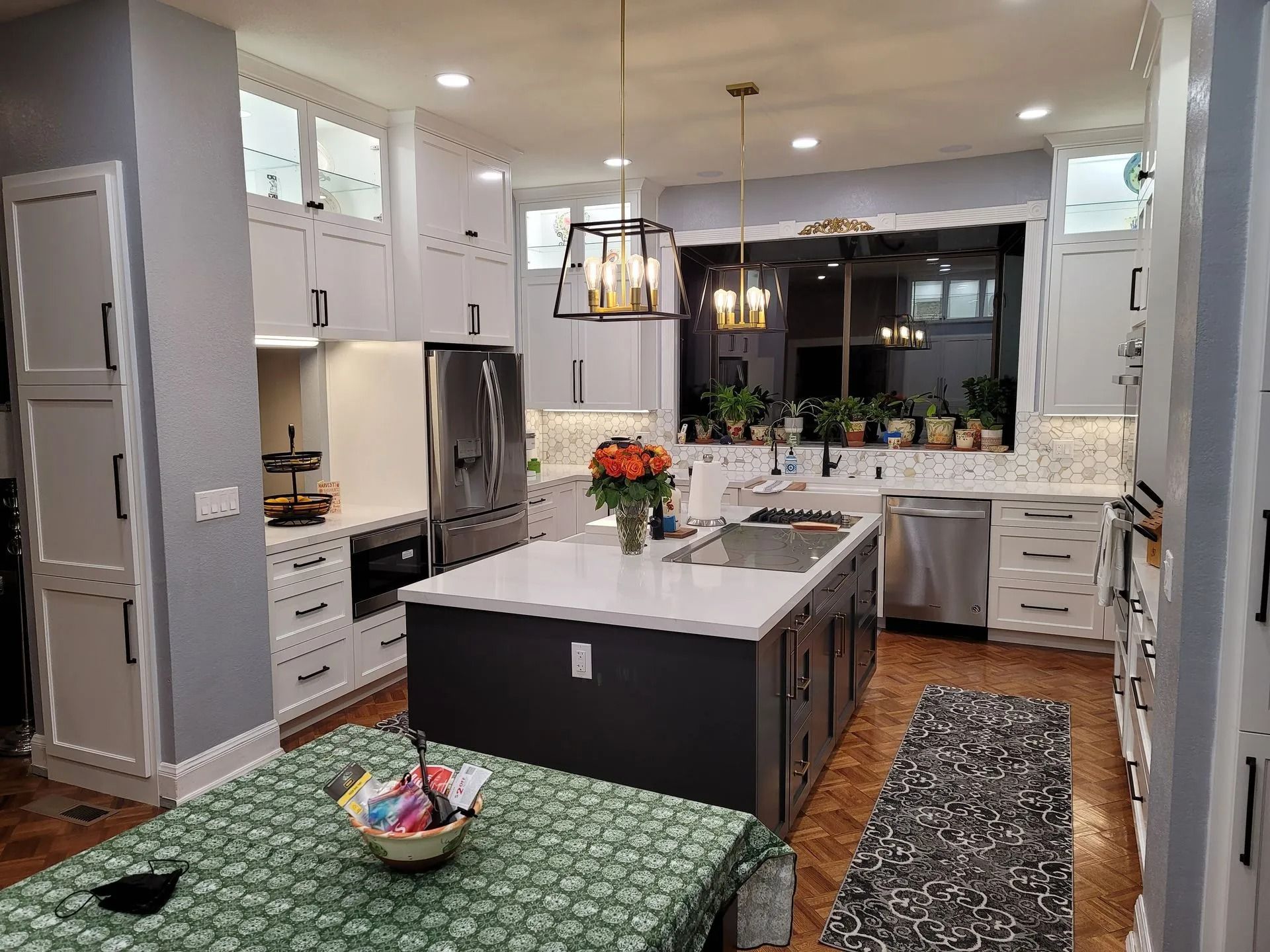 A kitchen with white cabinets, stainless steel appliances, a large island, and a table.
