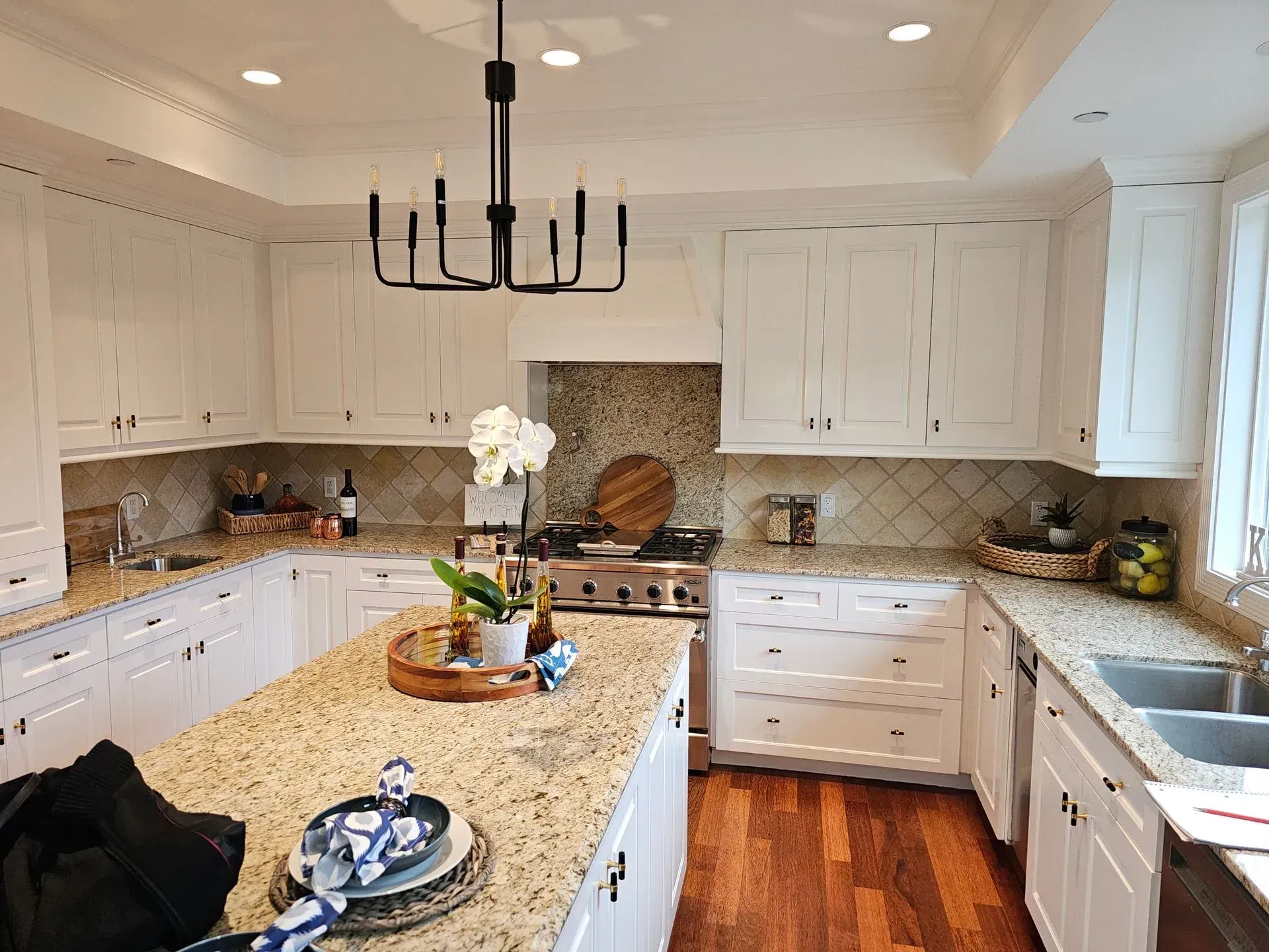 A kitchen with white cabinets, granite counter tops, stainless steel appliances, and a large island.