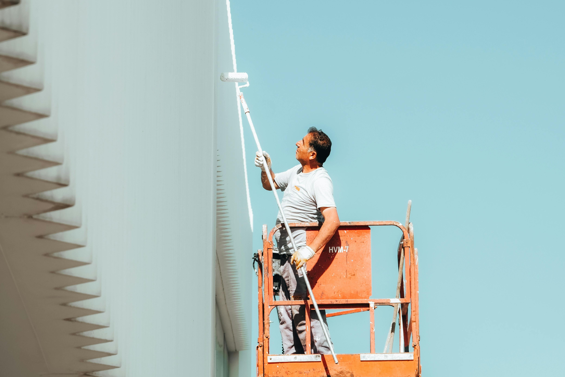 A man is painting a window on the side of a house.