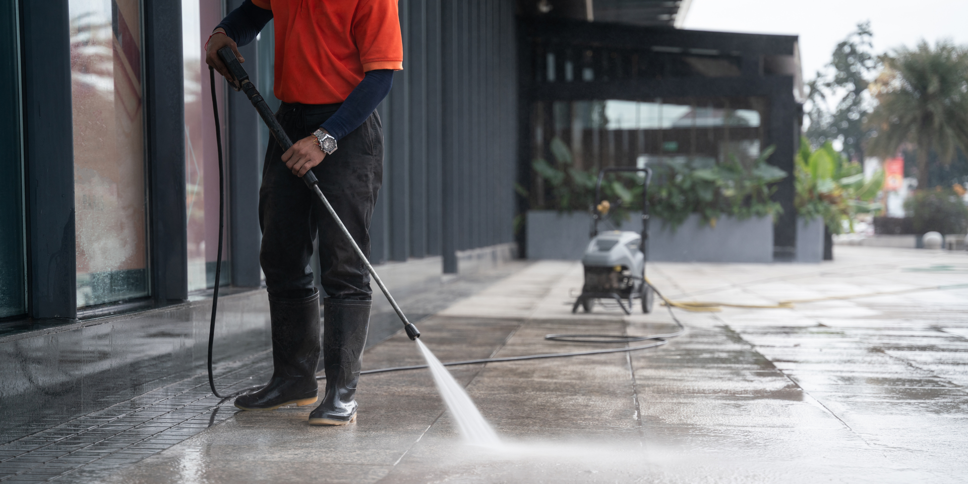 A person is cleaning a brick walkway with a high pressure washer.