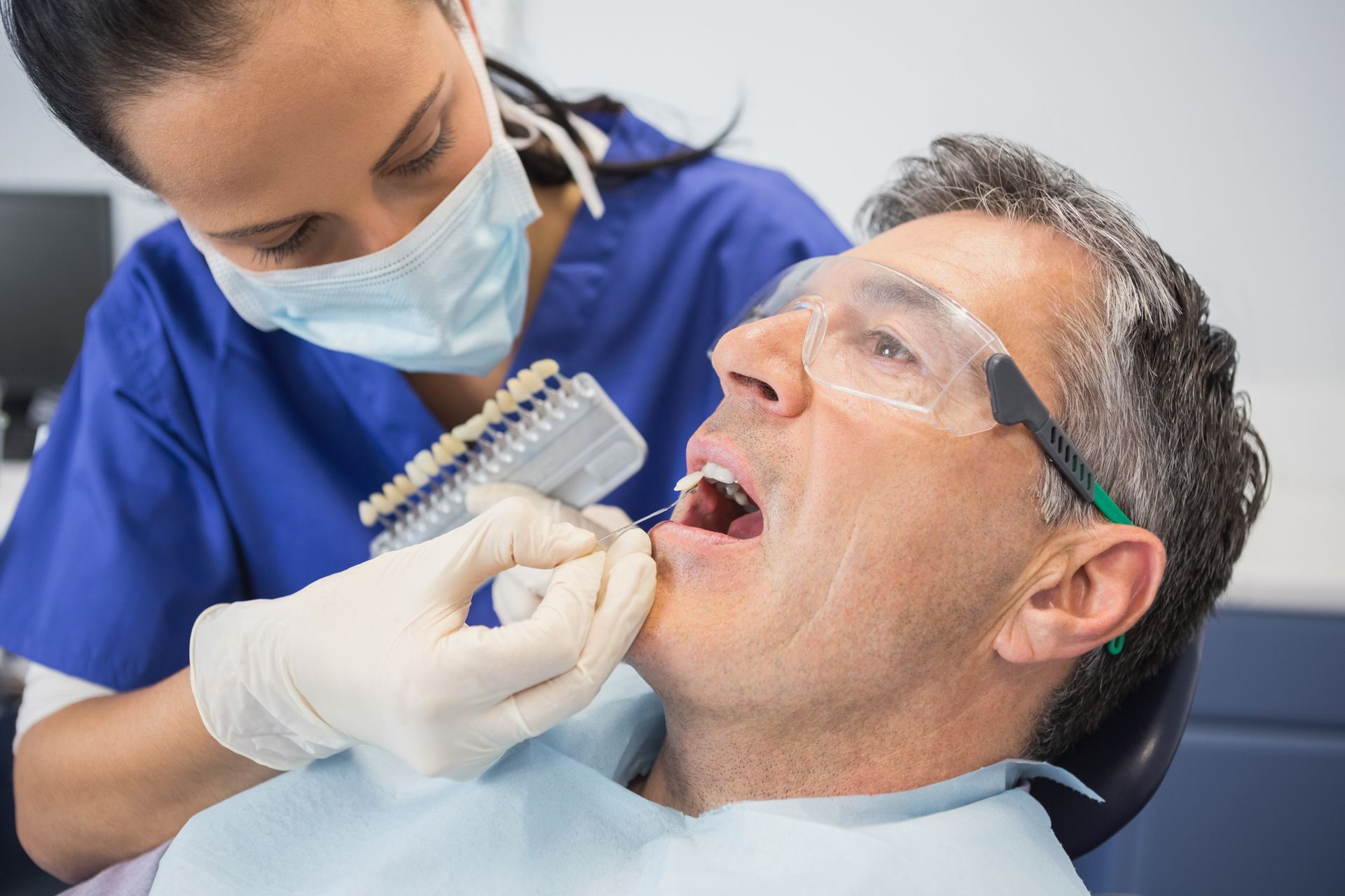 A dentist is performing a teeth whitening check on a patient.