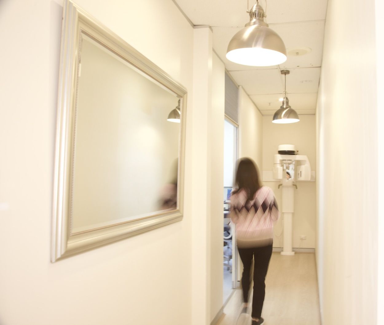 A woman is walking down a hallway in front of a mirror