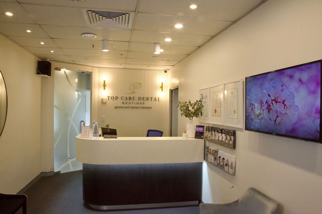 A dental office with a reception desk and a tv on the wall.