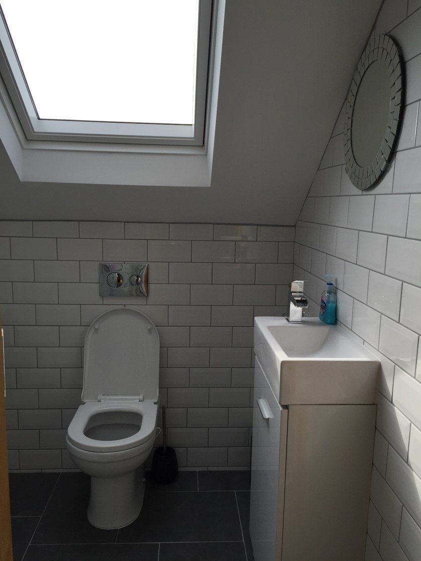 A bathroom with a toilet a sink and a skylight
