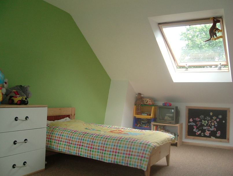 A bedroom with a bed a dresser and a skylight