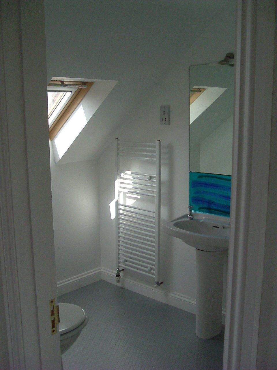 A bathroom with a toilet , sink , and towel rack.