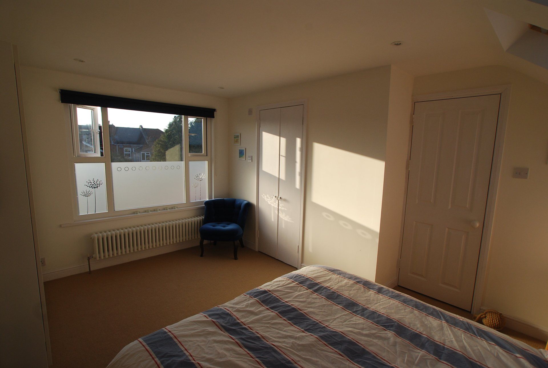 A bedroom with a bed , chair and window.