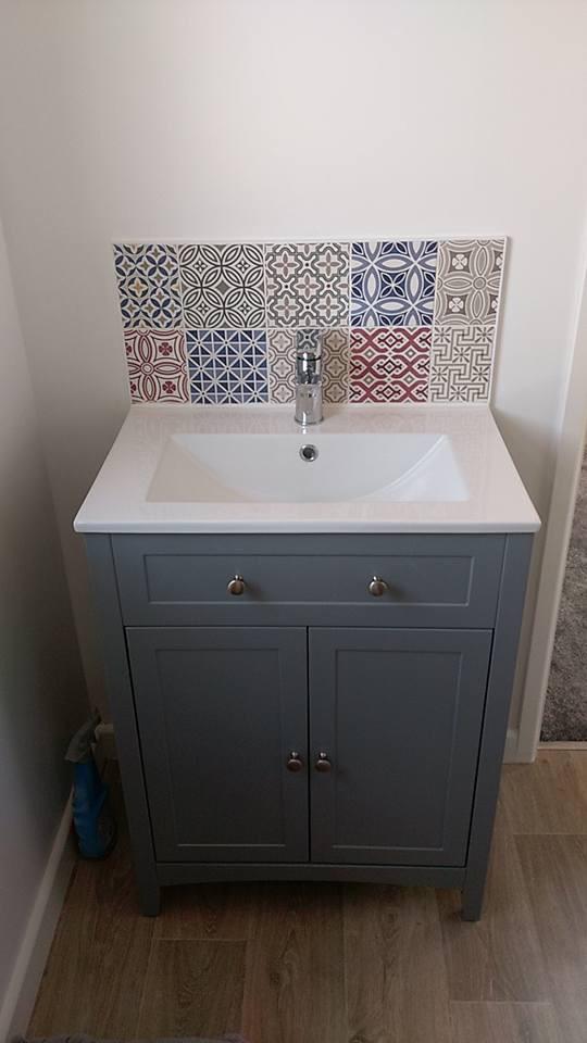 A loft bathroom vanity with a sink and tiles on the wall.