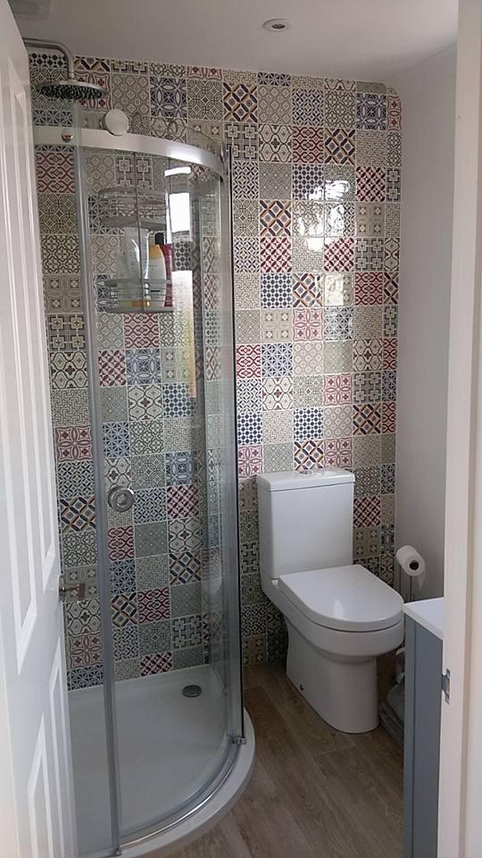 A bathroom with a toilet , shower and sink.