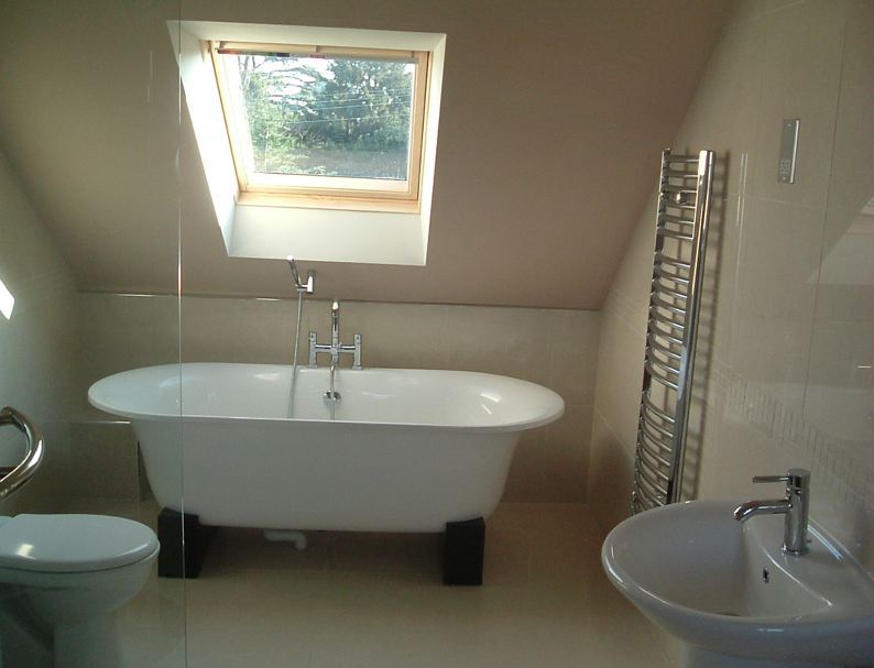 A bathroom with a bathtub , sink , toilet and skylight.