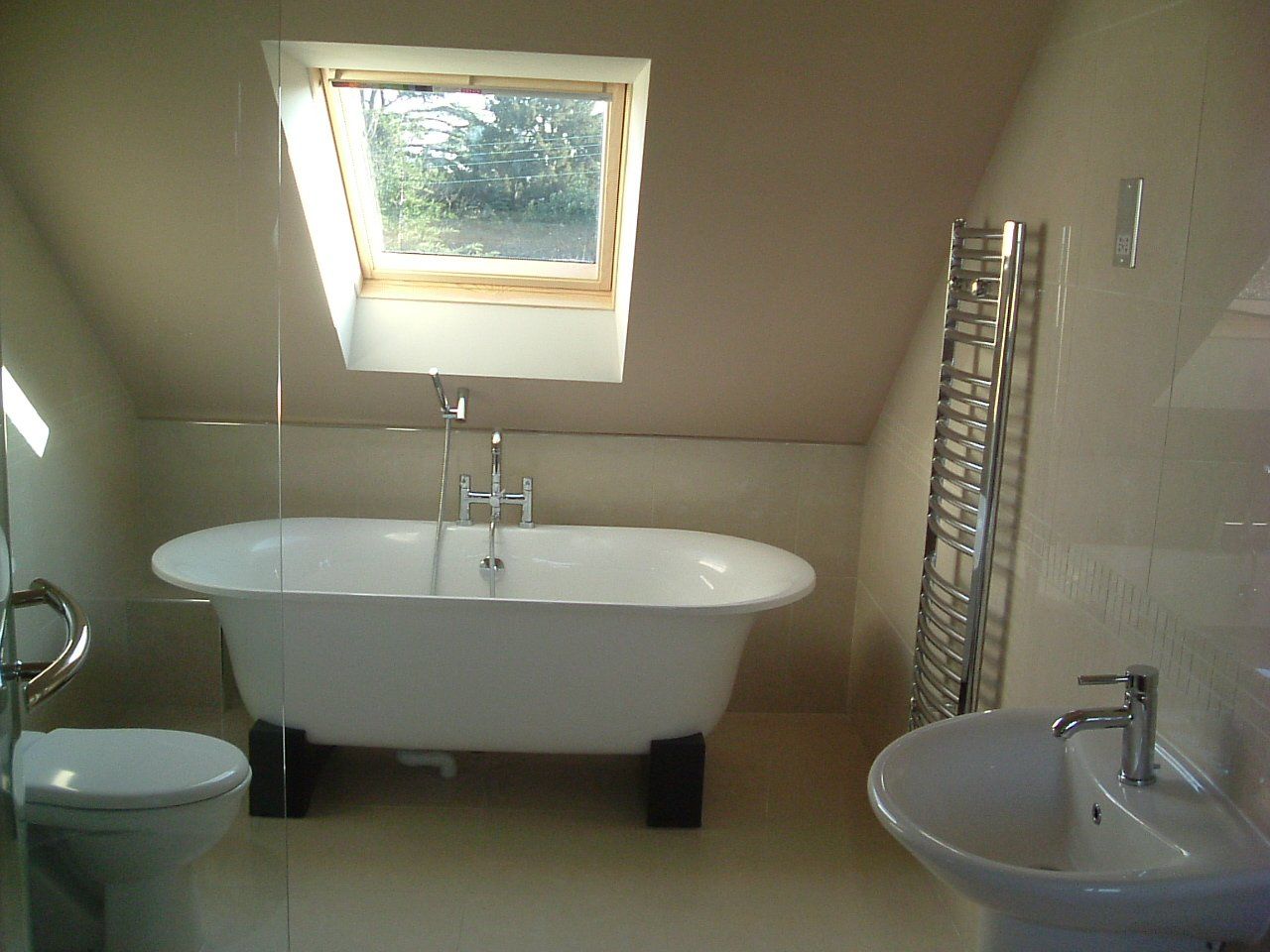 A bathroom with a bathtub toilet sink and skylight