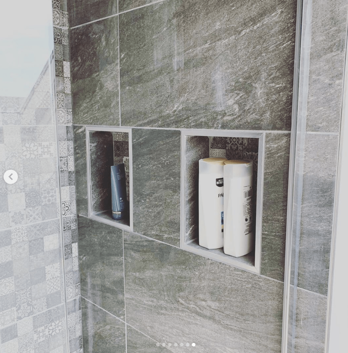 Two bottles of shampoo are sitting in a shower niche.