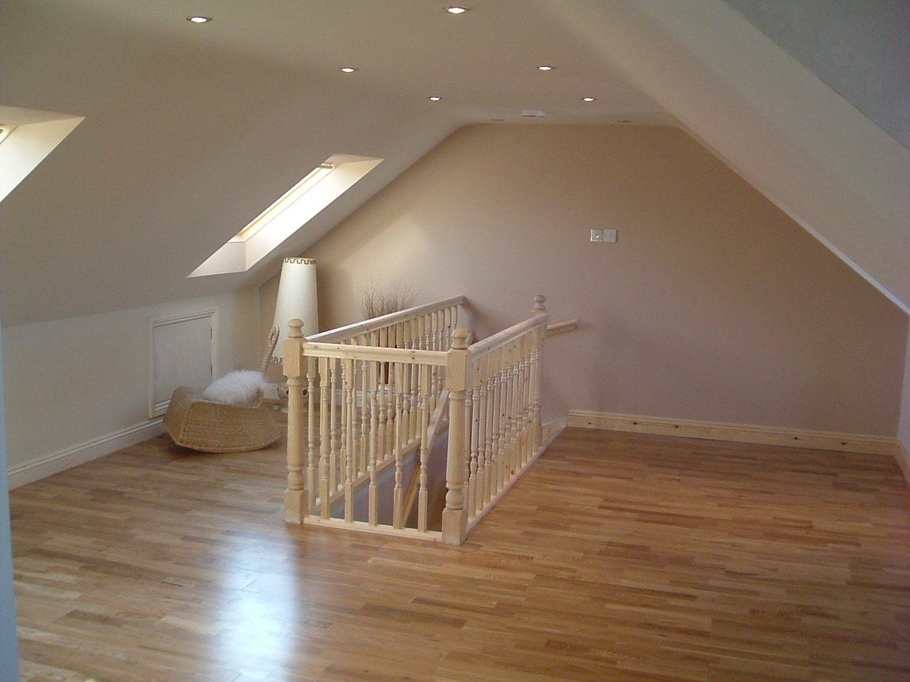 There is a staircase in the attic with a wooden railing.
