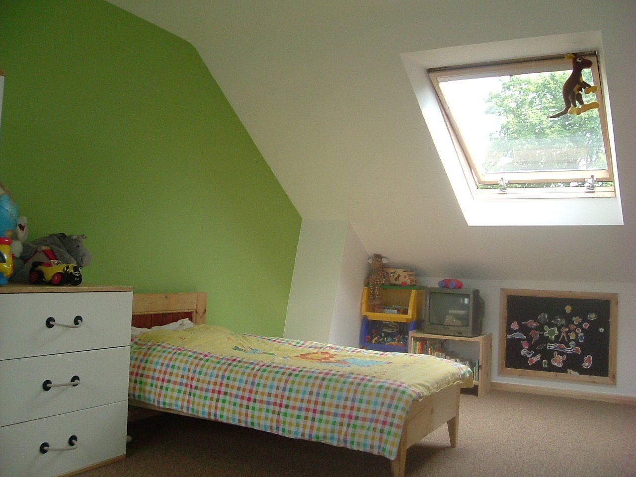 A bedroom with a bed a dresser and a skylight