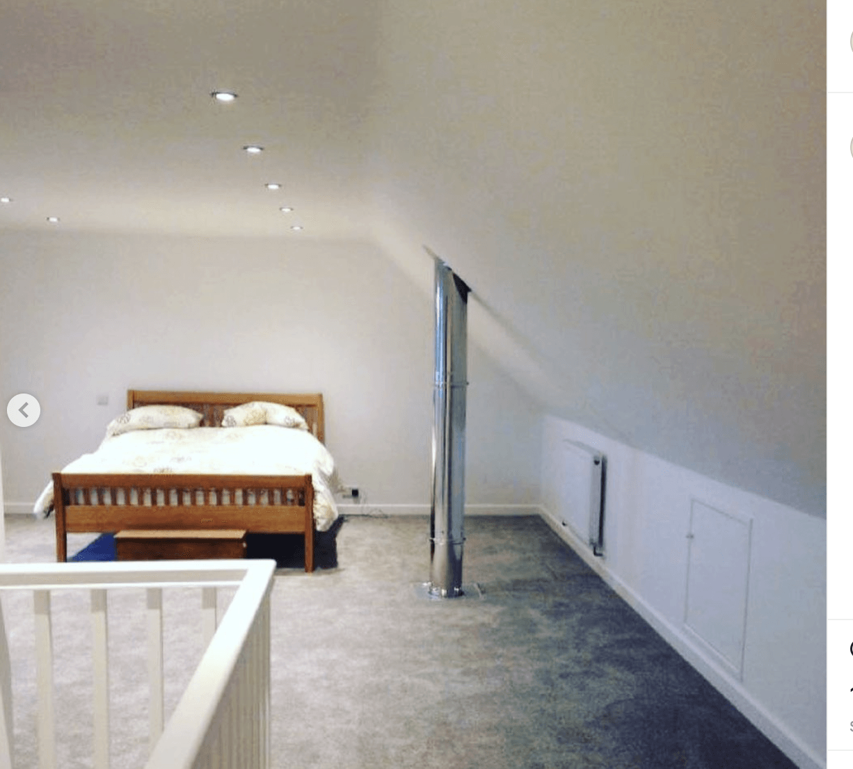 A bedroom with a slanted ceiling and a bed