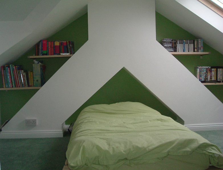 A bedroom with a bed and shelves with books on them