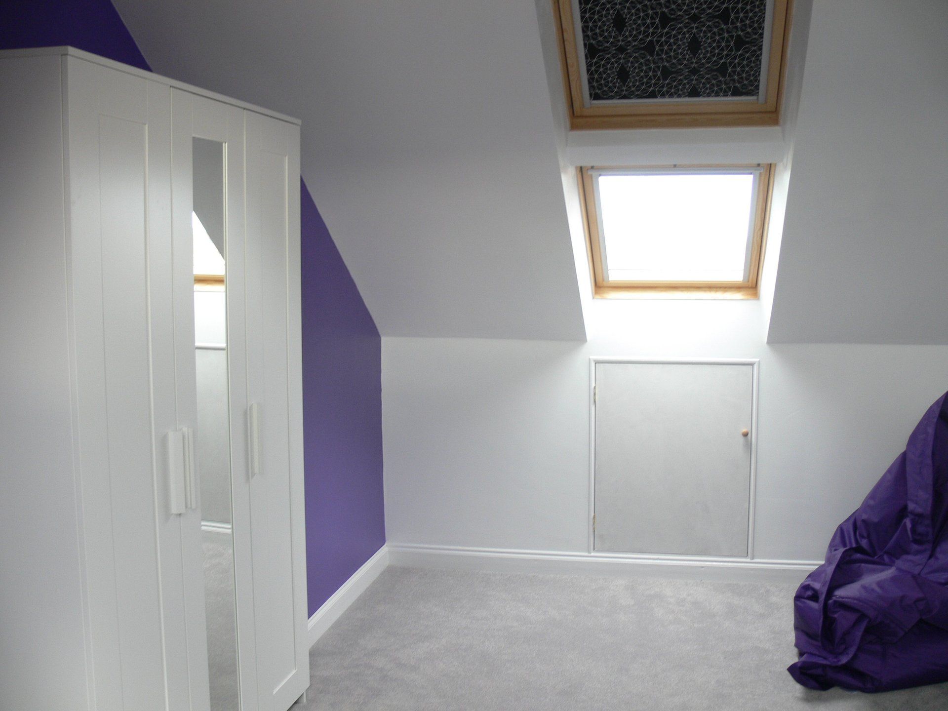 A Loft room with purple and white walls and a skylight