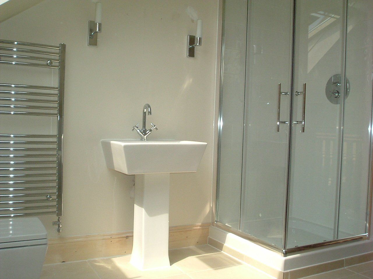 A bathroom with a pedestal sink and a walk in shower
