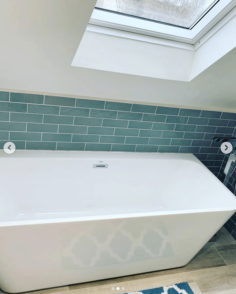 A bathtub is sitting under a skylight in a bathroom.