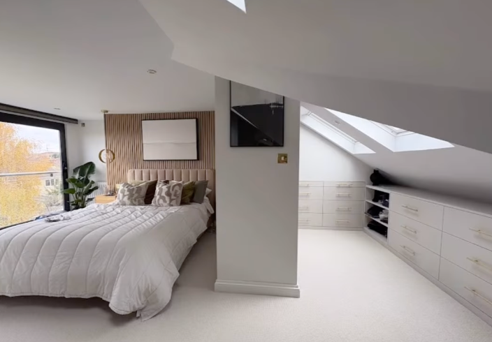 There is a large bed in the middle of the newly converted loft space.