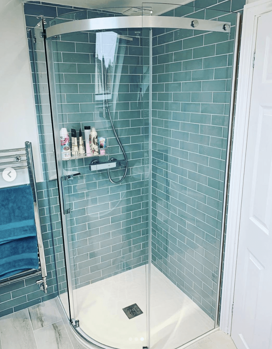 A bathroom with blue tiles and a curved shower stall.