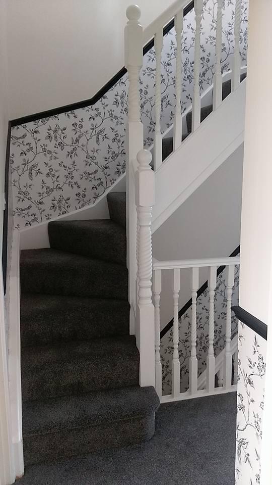 A loft stairs with a white railing and black carpet