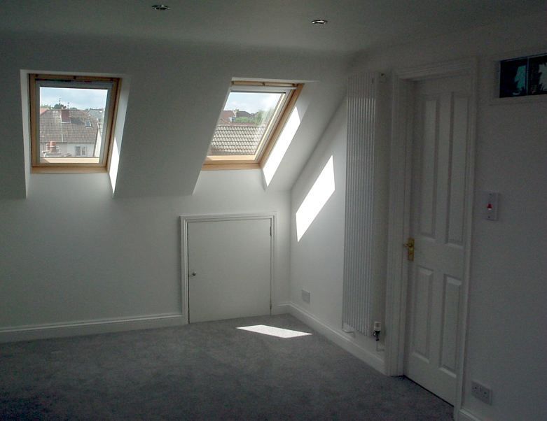 An empty room with two skylights and a door
