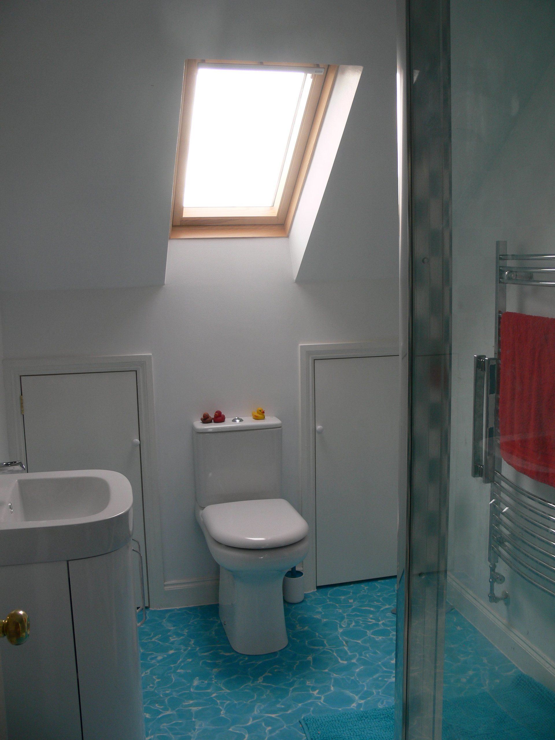 A bathroom with a toilet , sink and skylight