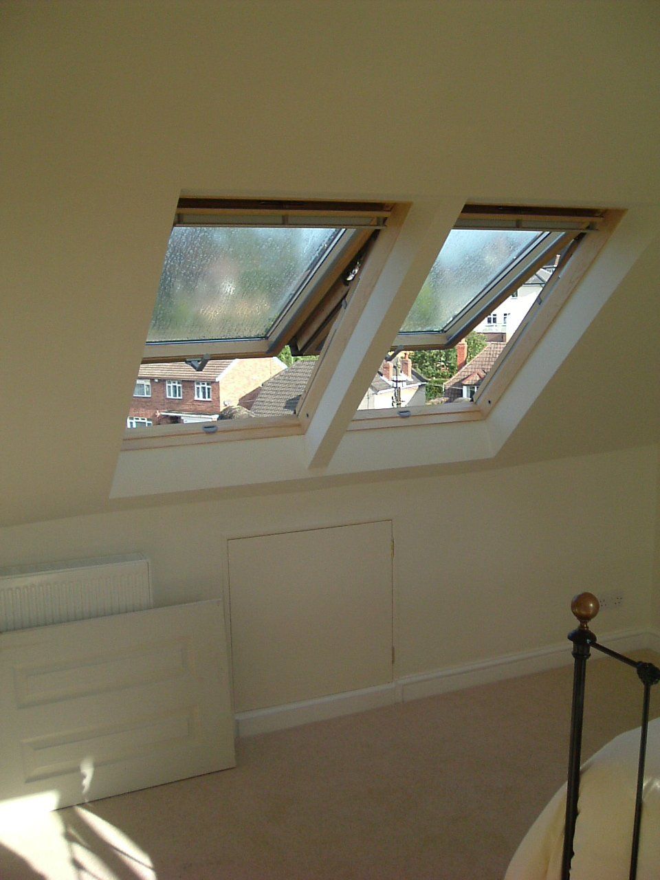 A bedroom with two skylights on the ceiling and a bed.