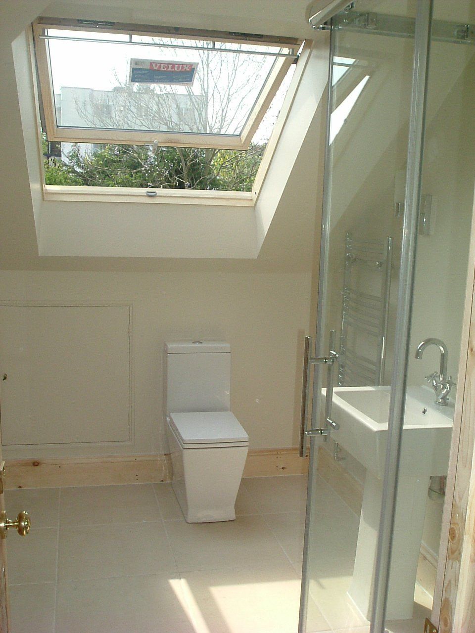 A bathroom with a toilet , sink , and skylight.