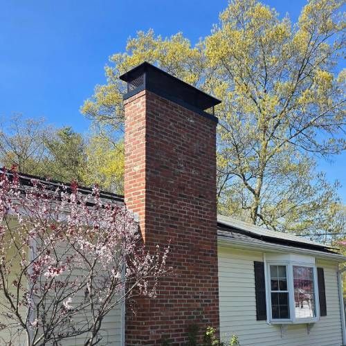 A white house with a brick chimney on the side of it.