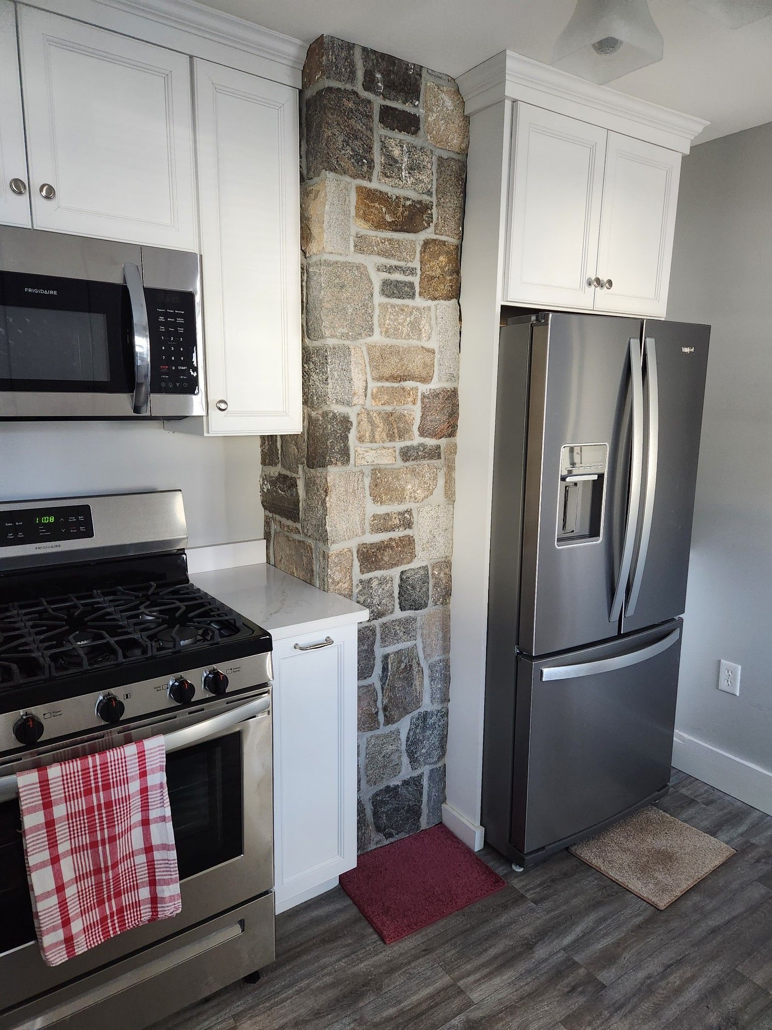 A kitchen with a stove , refrigerator and microwave