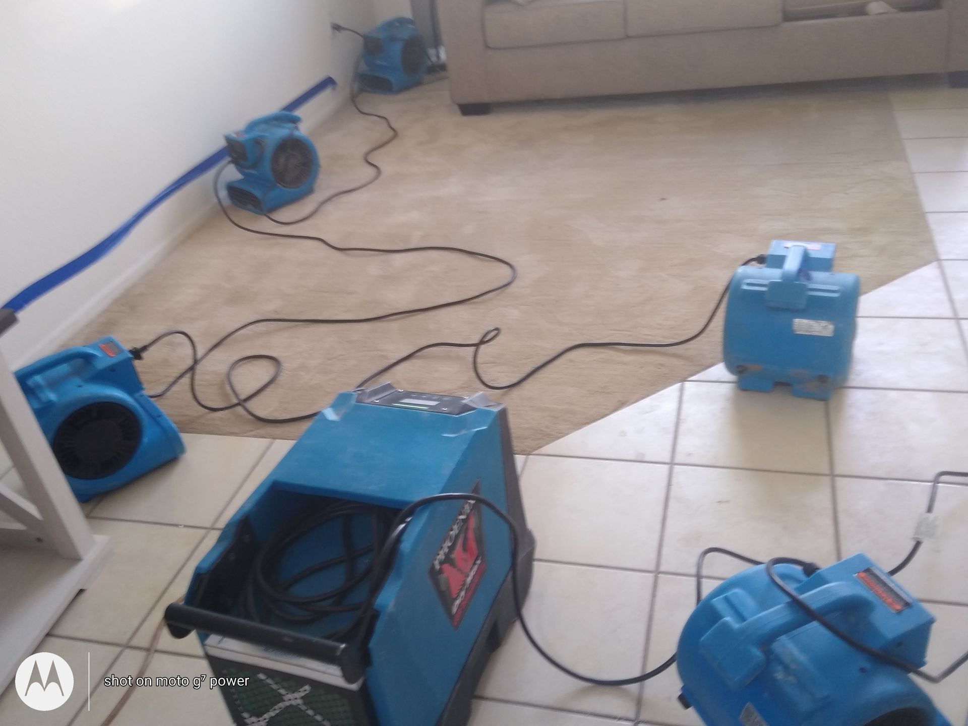 A motorola phone is sitting on a tiled floor next to a couch