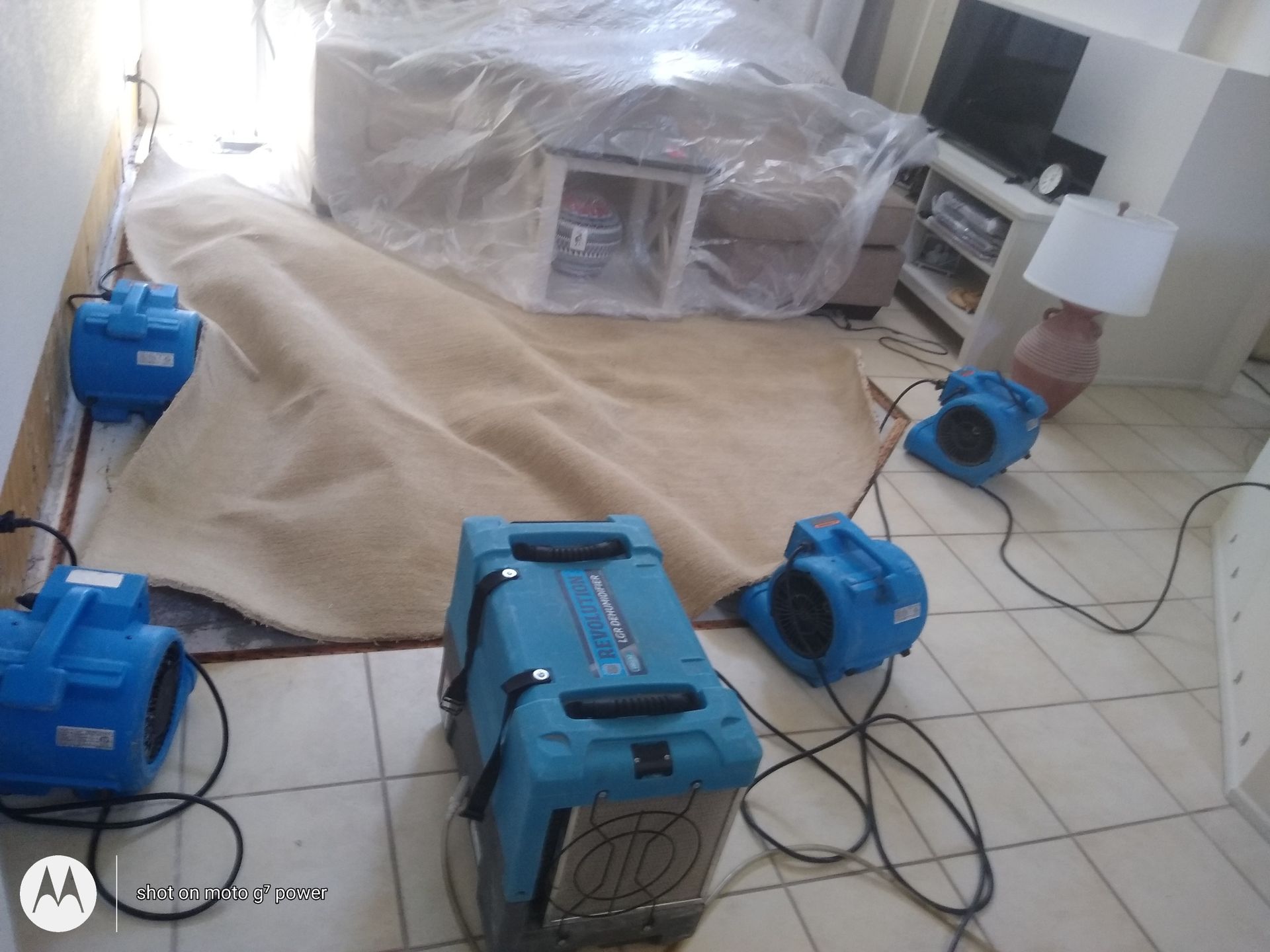 A living room filled with lots of appliances and a couch covered in plastic.