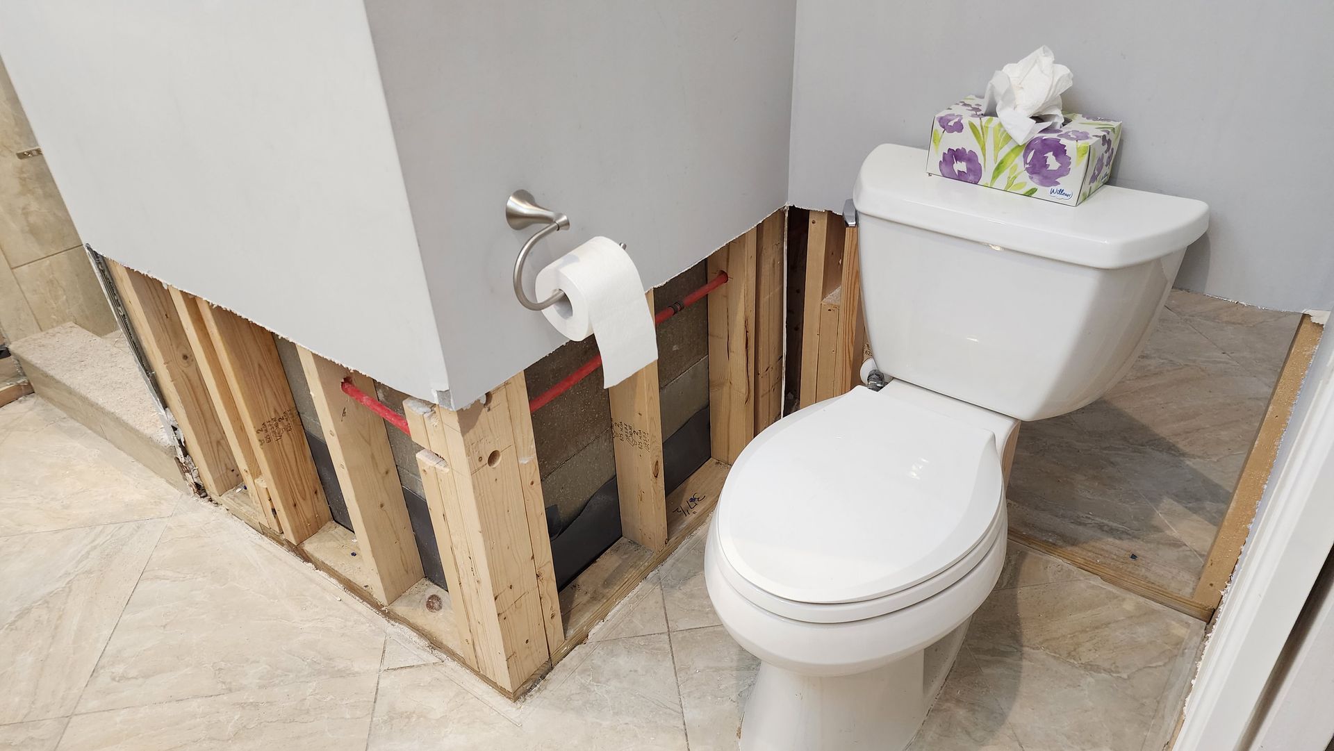 A toilet in a bathroom with a box of tissues on top of it.