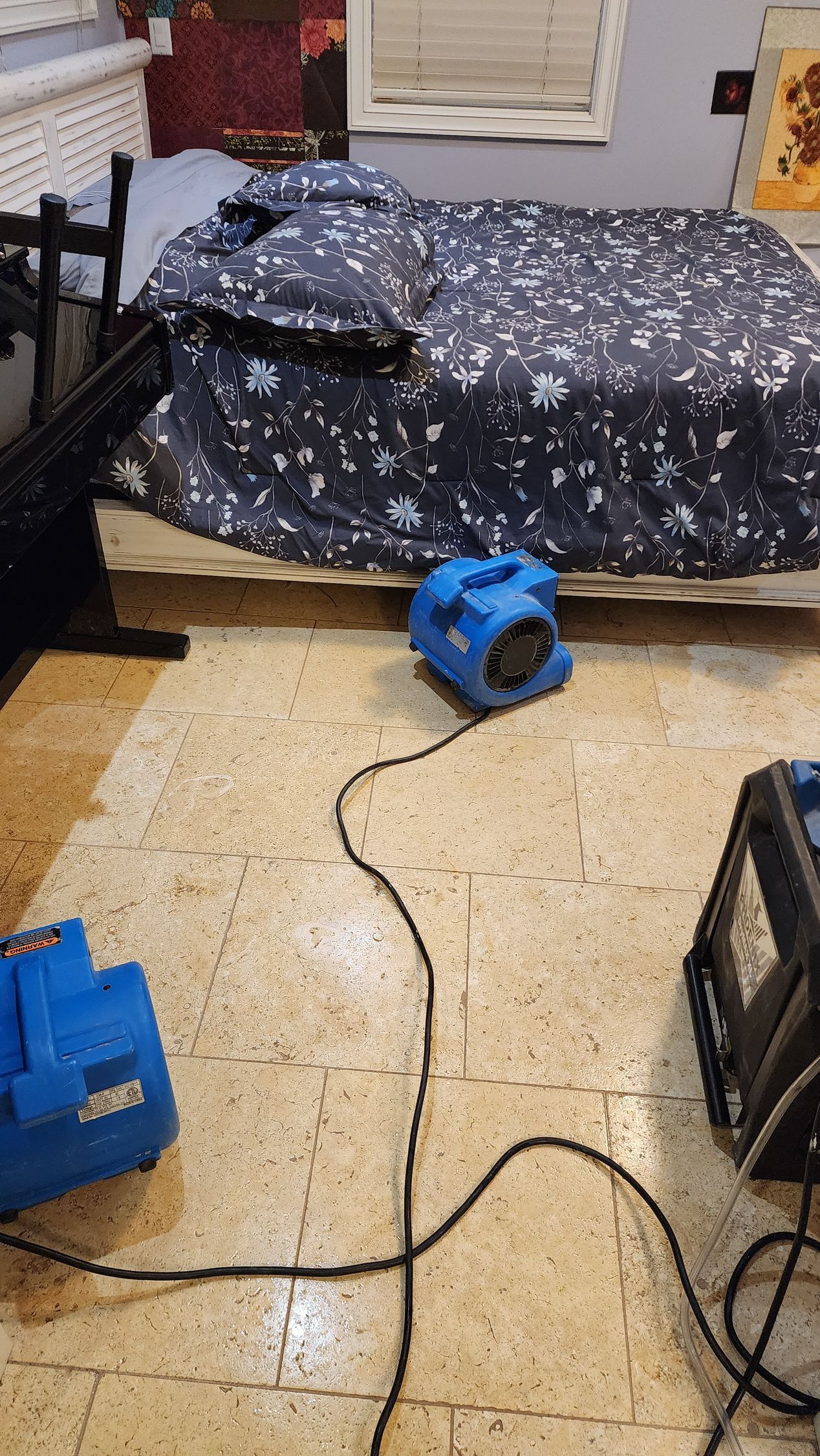 A bedroom with a bed and a fan on the floor.