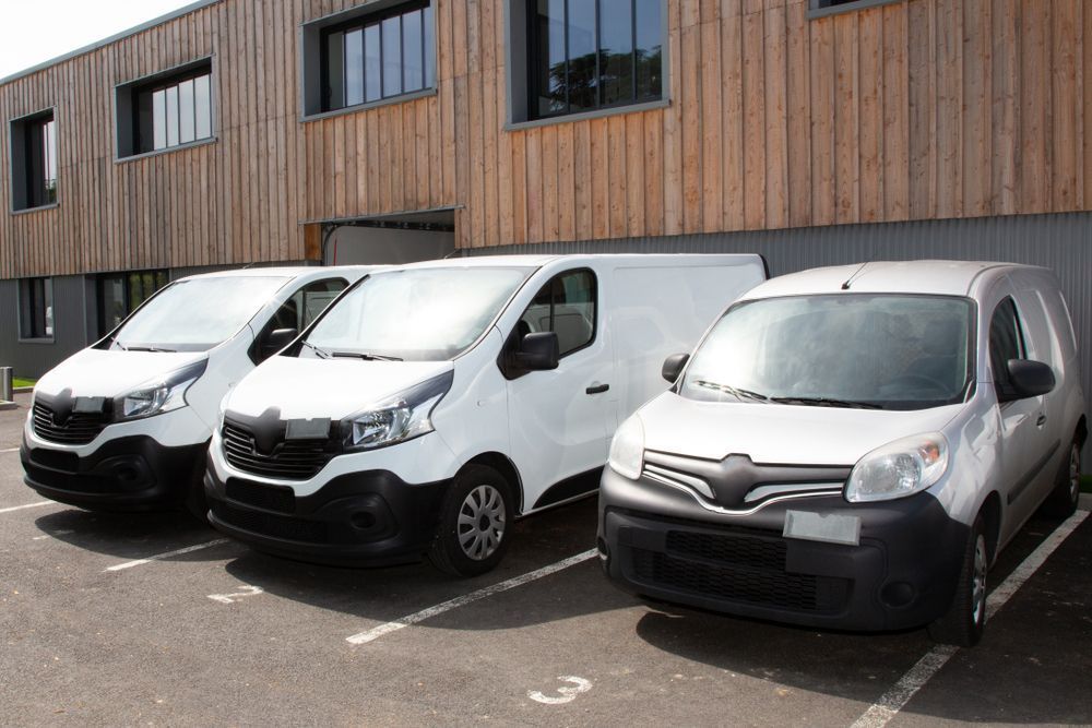 Three White Vans Are Parked in a Parking Lot in Front of a Building — R2B Heavy Vehicle Driving School In Marian, QLD