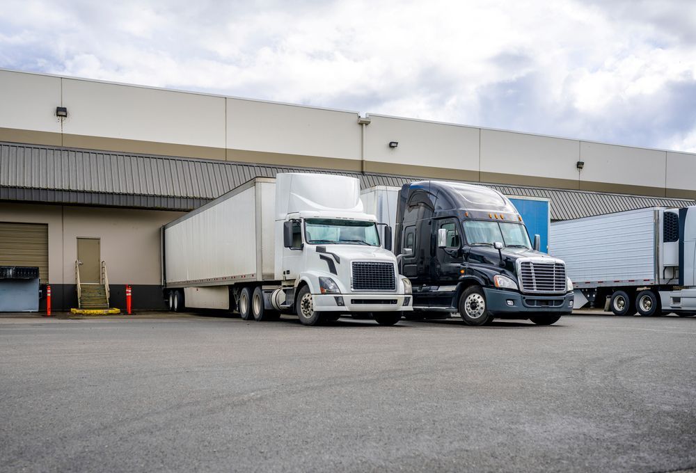 Two Semi Trucks Are Parked in Front of a Warehouse — R2B Heavy Vehicle Driving School In Paget, QLD