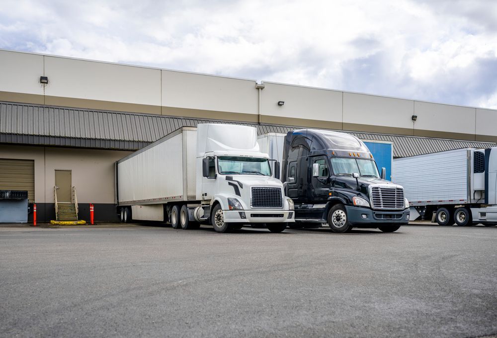 Two Semi Trucks Are Parked In Front Of A Warehouse — R2B Heavy Vehicle Driving School In Moranbah, QLD