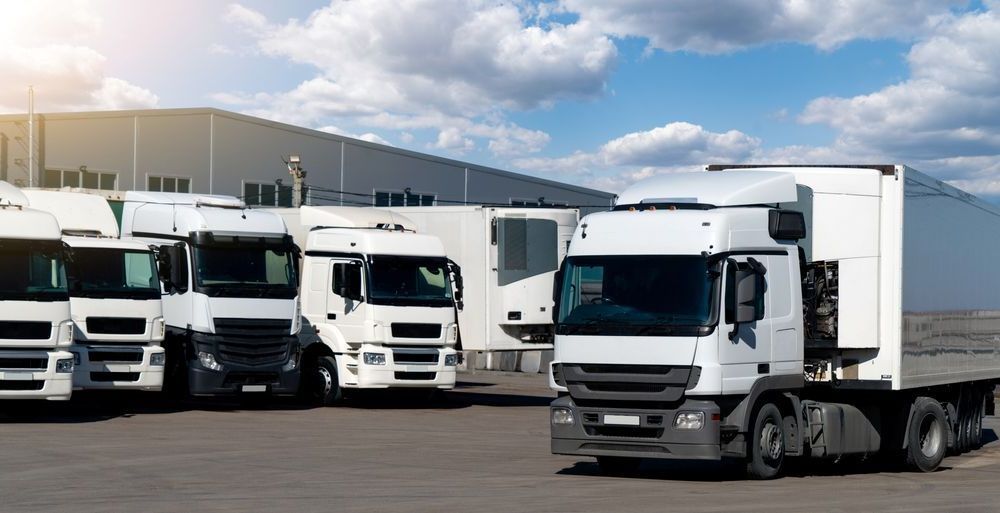 A Row of Semi Trucks Parked in a Parking Lot in Front of a Building — R2B Heavy Vehicle Driving School In Moranbah, QLD