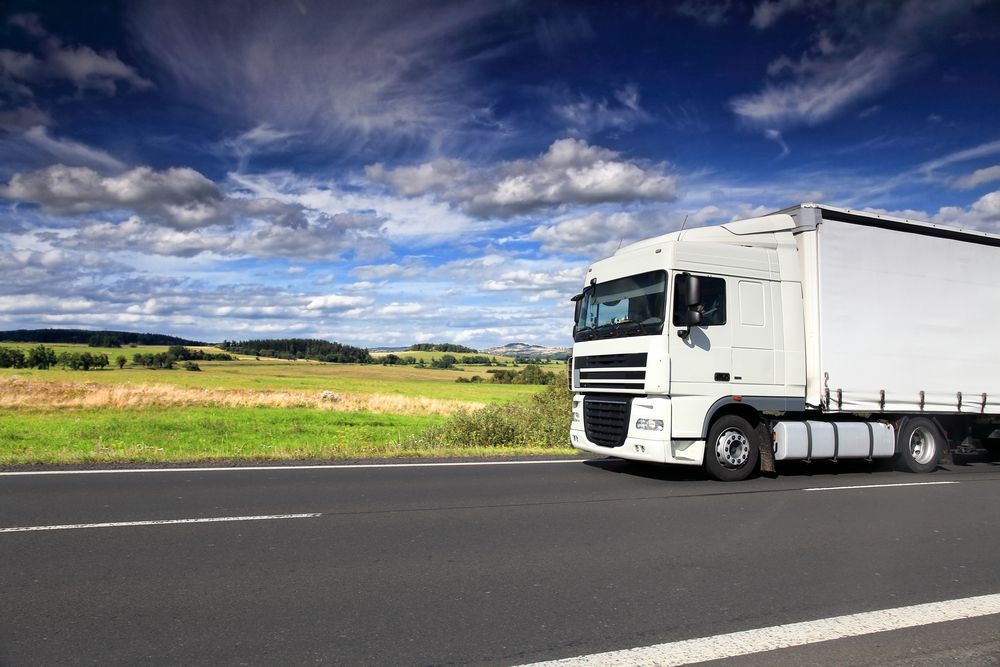 A White Semi Truck Is Driving Down A Highway Next To A Field — R2B Heavy Vehicle Driving School in Sarina, QLD