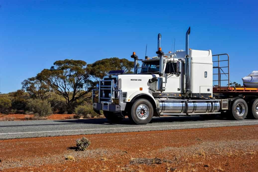 A White Semi Truck Is Driving Down A Road In The Desert — R2B Heavy Vehicle Driving School In Mackay, QLD