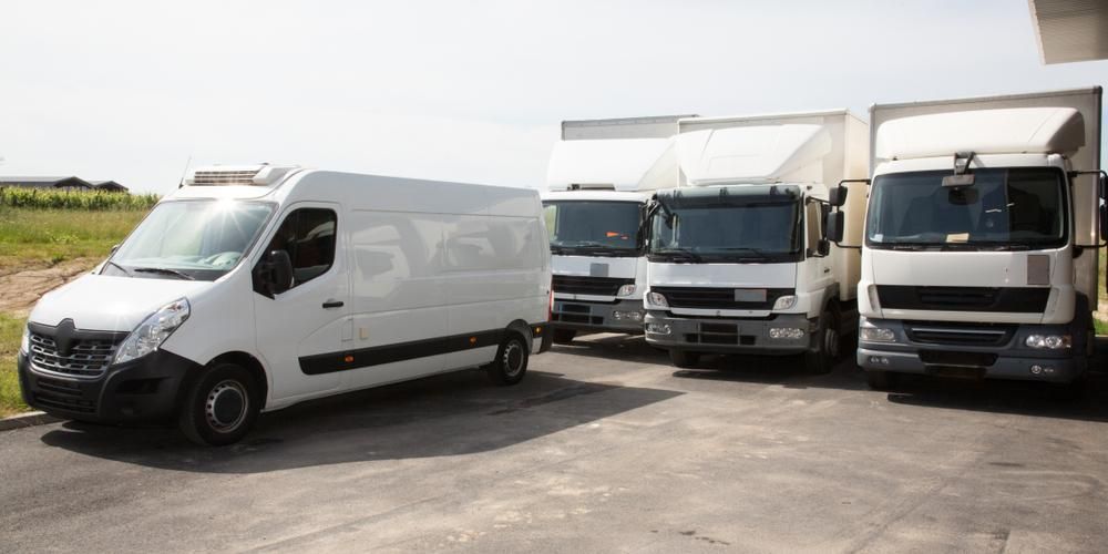 A Row Of White Trucks Parked Next To Each Other In A Parking Lot — R2B Heavy Vehicle Driving School In Mackay, QLD