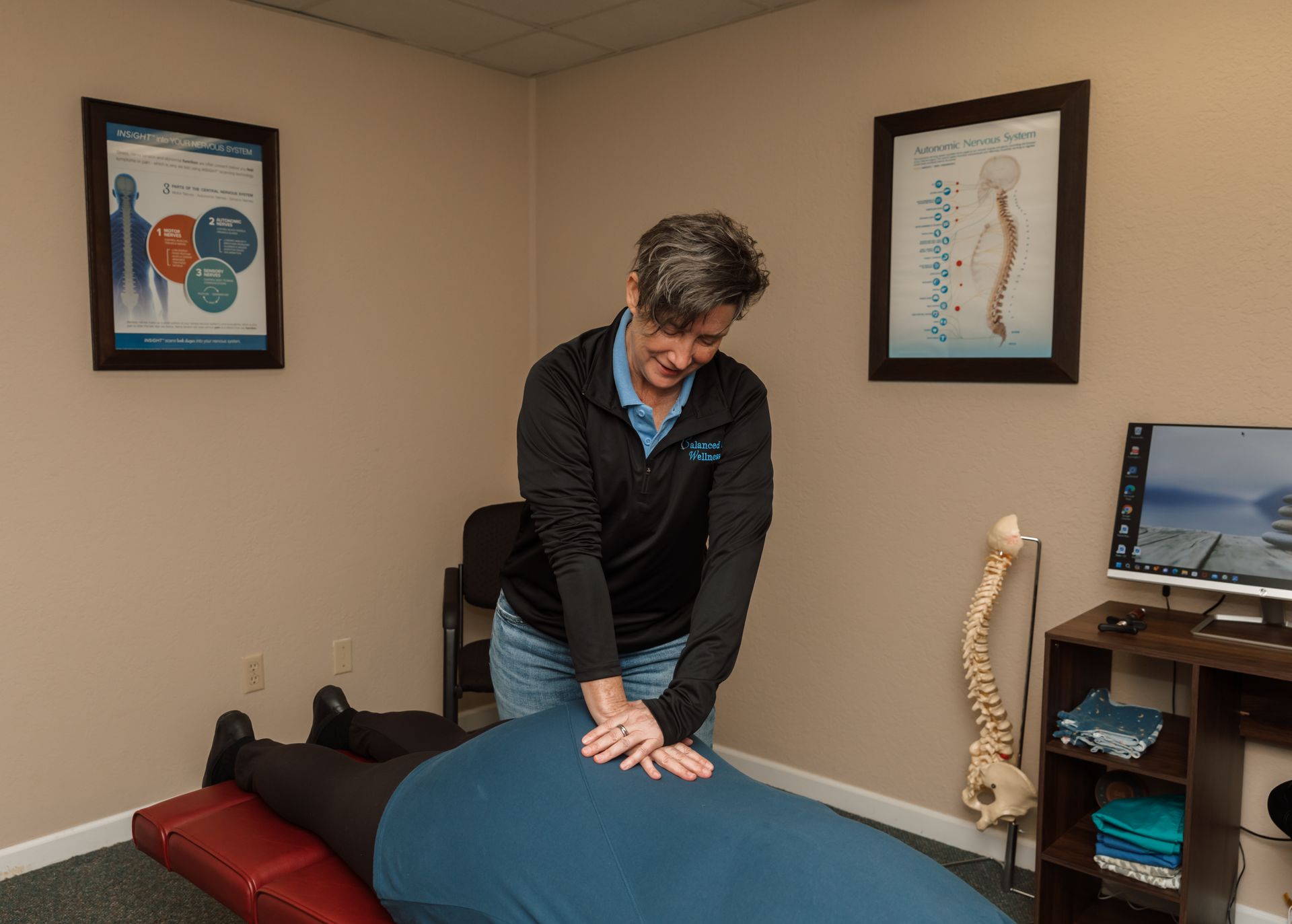 A woman is giving a person a massage on a table in a room.