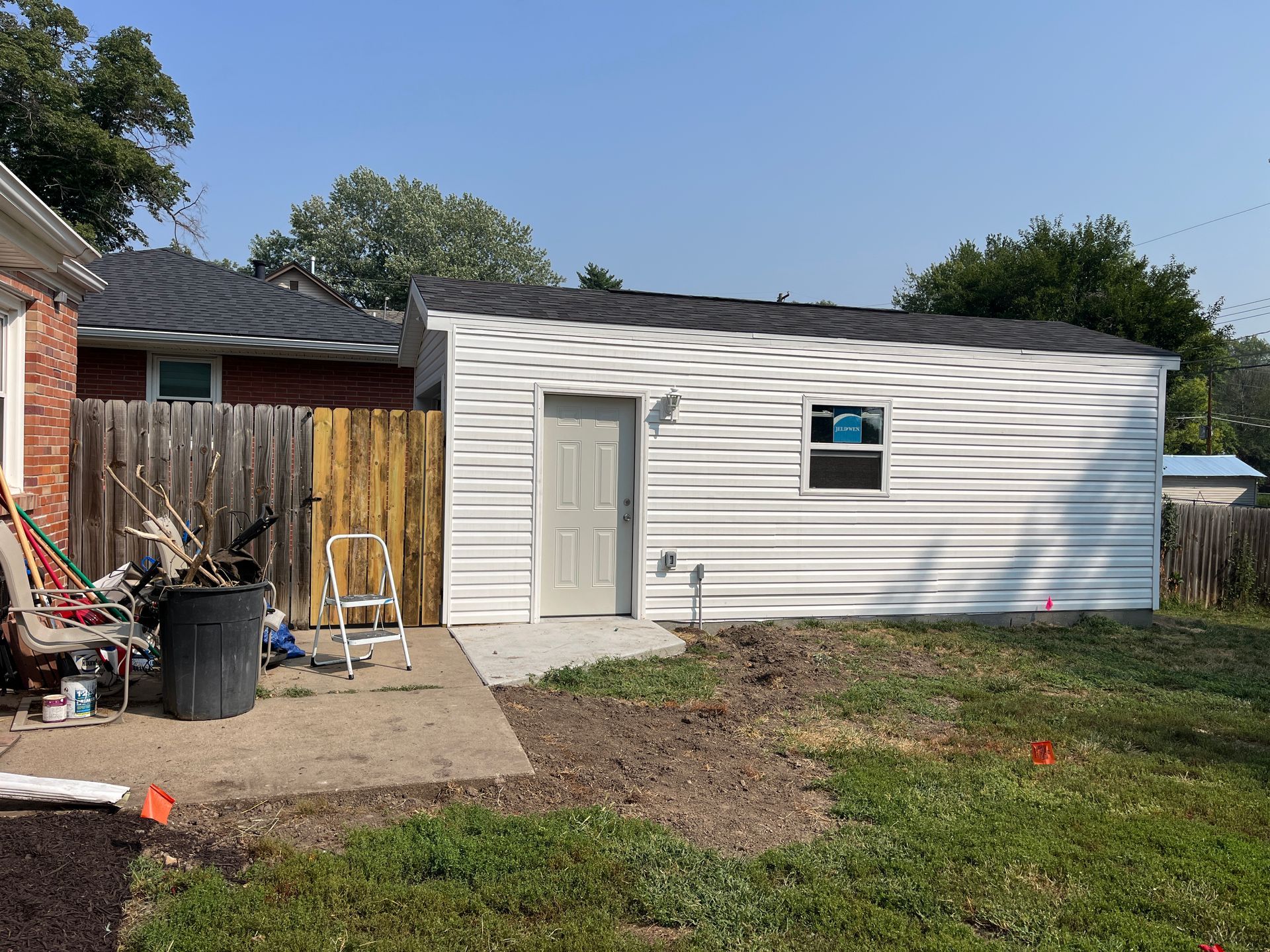 White shed with gray door and small window in backyard.