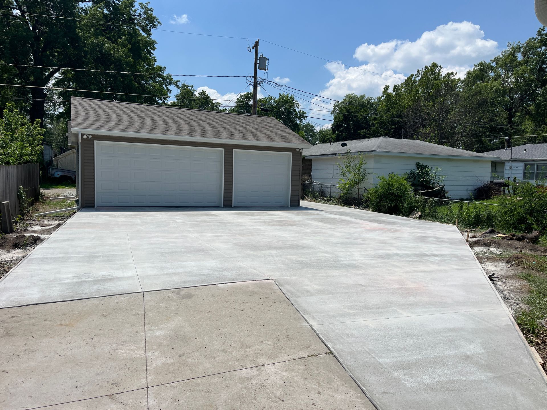 A concrete driveway leading to a garage with two garage doors